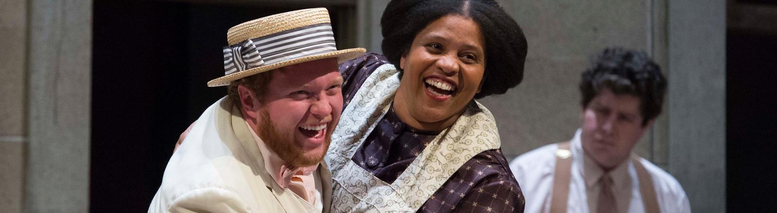 Two singers of the opera chorus dancing and smiling